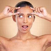 01-playful-woman-framing-face-with-her-fingers-2026-03-25-08-12-14-utc Beauty health, surprise and woman forehead wrinkles with a female squeeze face with shock. Isolated.